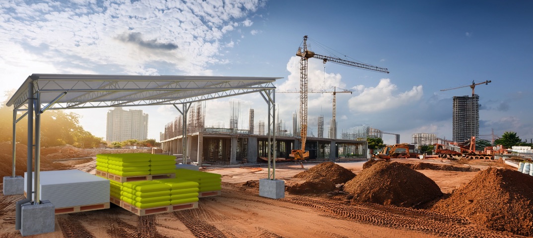 Construction site with building materials, aggregates, cranes, and sheet materials